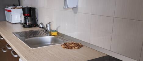 Una cocina con un lavamanos de acero inoxidable, una cafetera y un dispensador de jabón para lavar platos.
