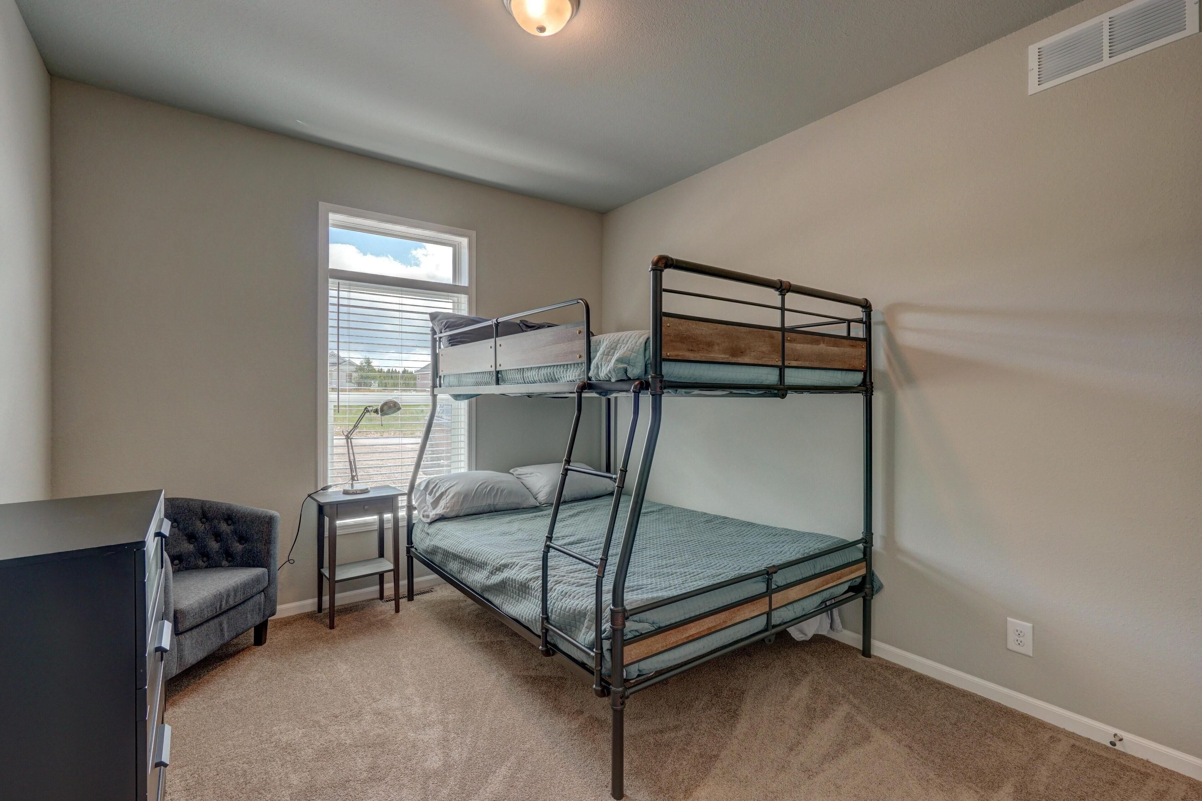A bedroom with a bunk bed, a desk, and a chair.