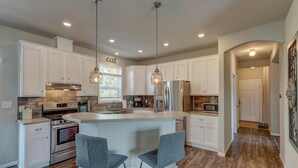 A modern kitchen with white cabinets, stainless steel appliances, and a central island with bar stools.