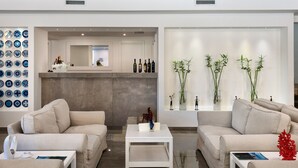 A modern living room with two beige sofas, a white coffee table, and a wall with blue ceramic plates. - Hotel Isabella (Sant'Agnello)