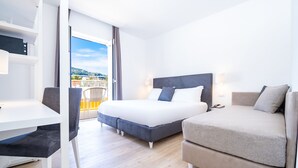 A hotel room with a bed, a sofa, a desk, and a balcony with a view. - Hotel Isabella (Sant'Agnello)
