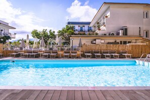 A swimming pool with lounge chairs and umbrellas, surrounded by buildings with balconies and outdoor furniture. - Hotel Isabella (Sant'Agnello)