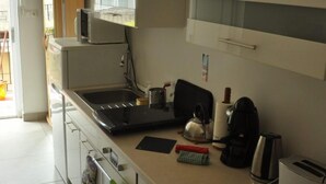 A modern kitchen with white cabinets, a microwave, a stove, and a coffee maker. - Classical Budapest apartment in the old Pest (Budapest)