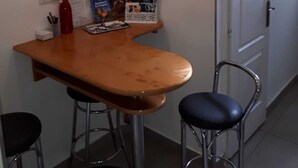 A small, compact room with a wooden table and two bar stools. There is a white door on the right and a small shelf with books and a red bottle on the left. - Classical Budapest apartment in the old Pest (Budapest)