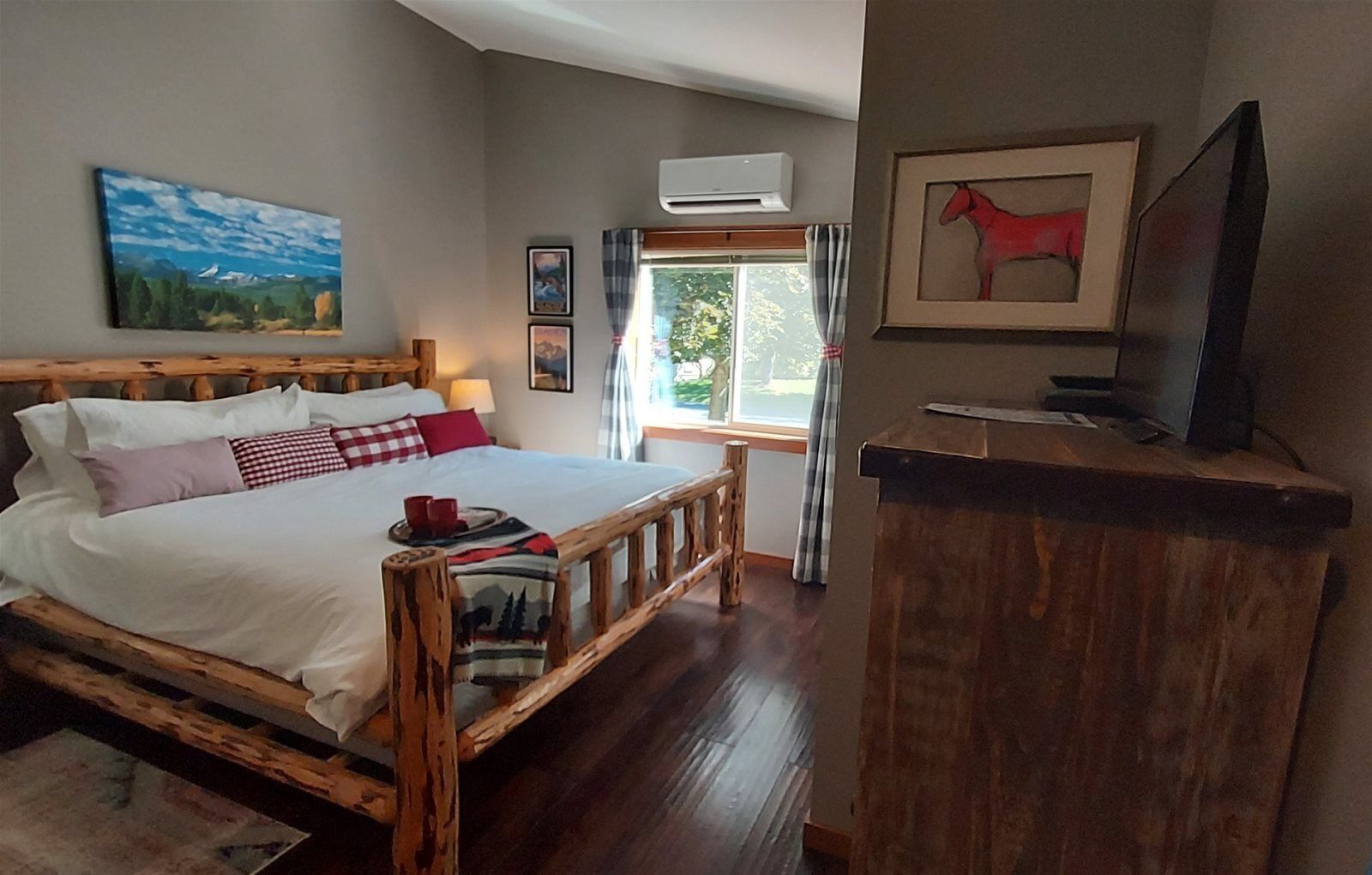 Une chambre à coucher avec un lit en bois, une télévision et une fenêtre avec des rideaux.