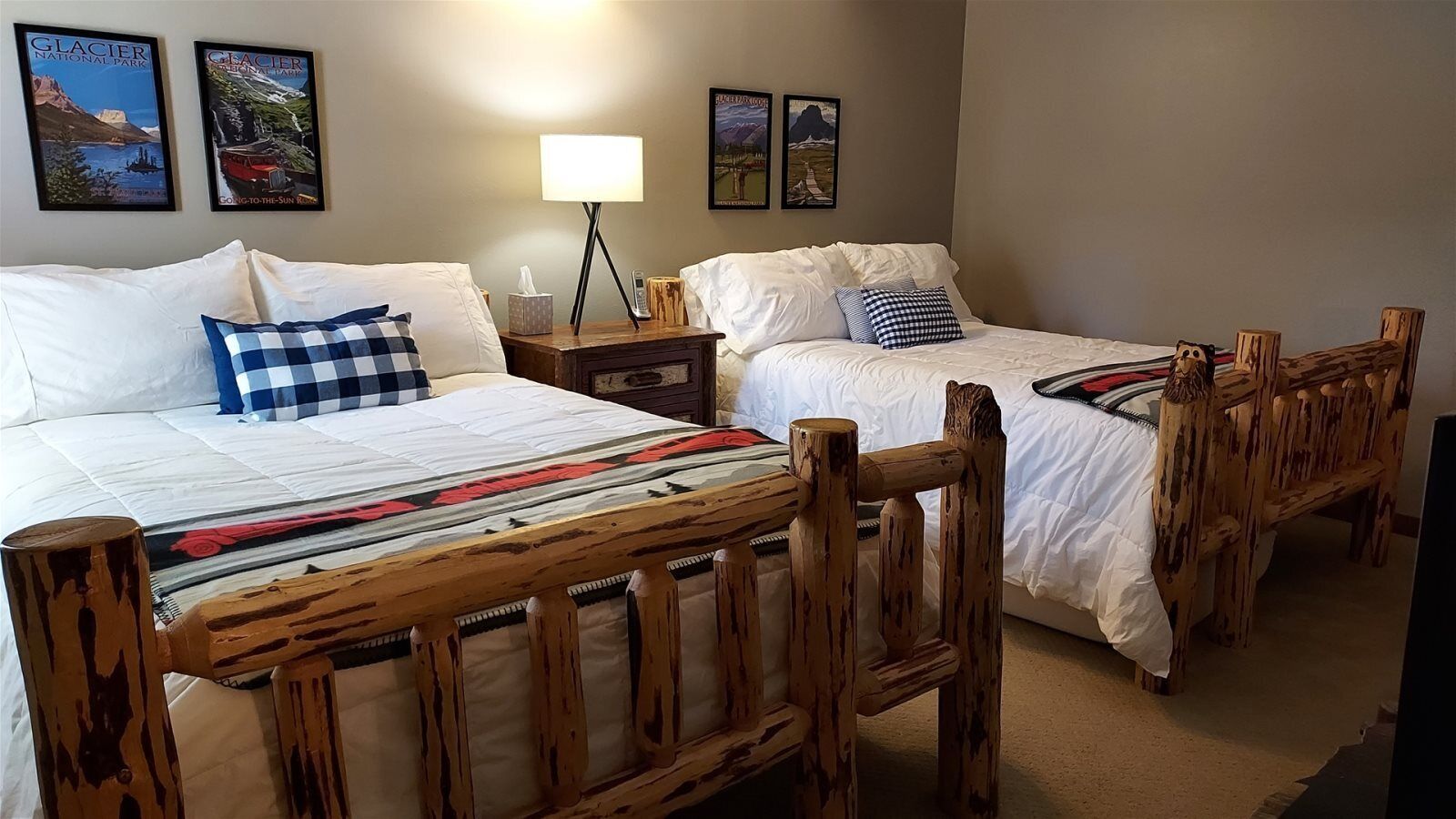 Une chambre d’hôtel avec deux lits en bois, du linge de lit blanc et une table de chevet avec une lampe.