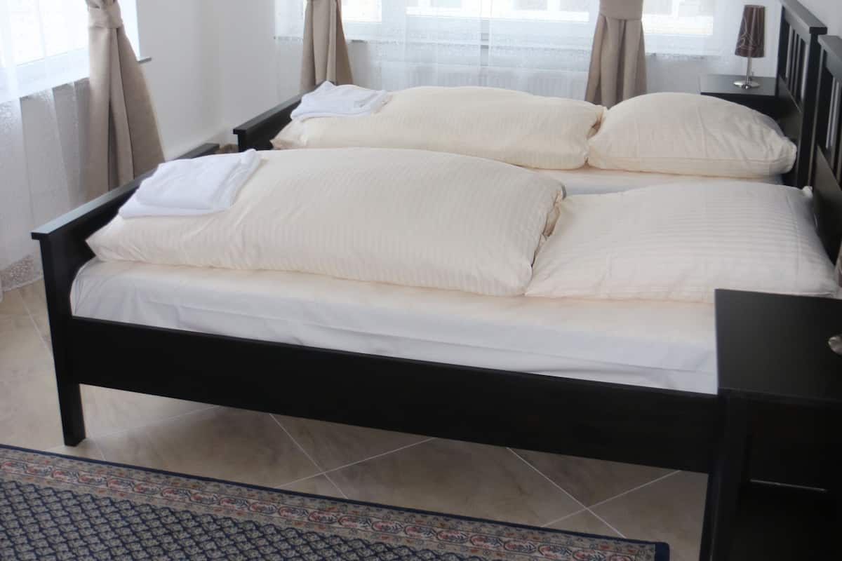 Een slaapkamer met een bed, gordijnen, een nachtkastje en een bedtafel.