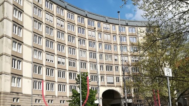 Ein mehrgeschossiges Gebäude mit einheitlicher Fassade, einem Fußgängerweg und einem Fahrradstellplatz.