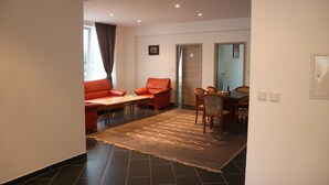 Ein modernes Wohnzimmer mit Sofa, Sesseln, Couchtisch und Teppich.