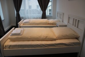 A bedroom with two single beds, each with a pillow and a folded towel. - Bed Budget City Center Hannover - Hostel (Hannover)