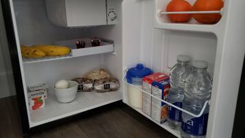 Een koelkast met bananen, brood, eieren, melk en waterflessen.