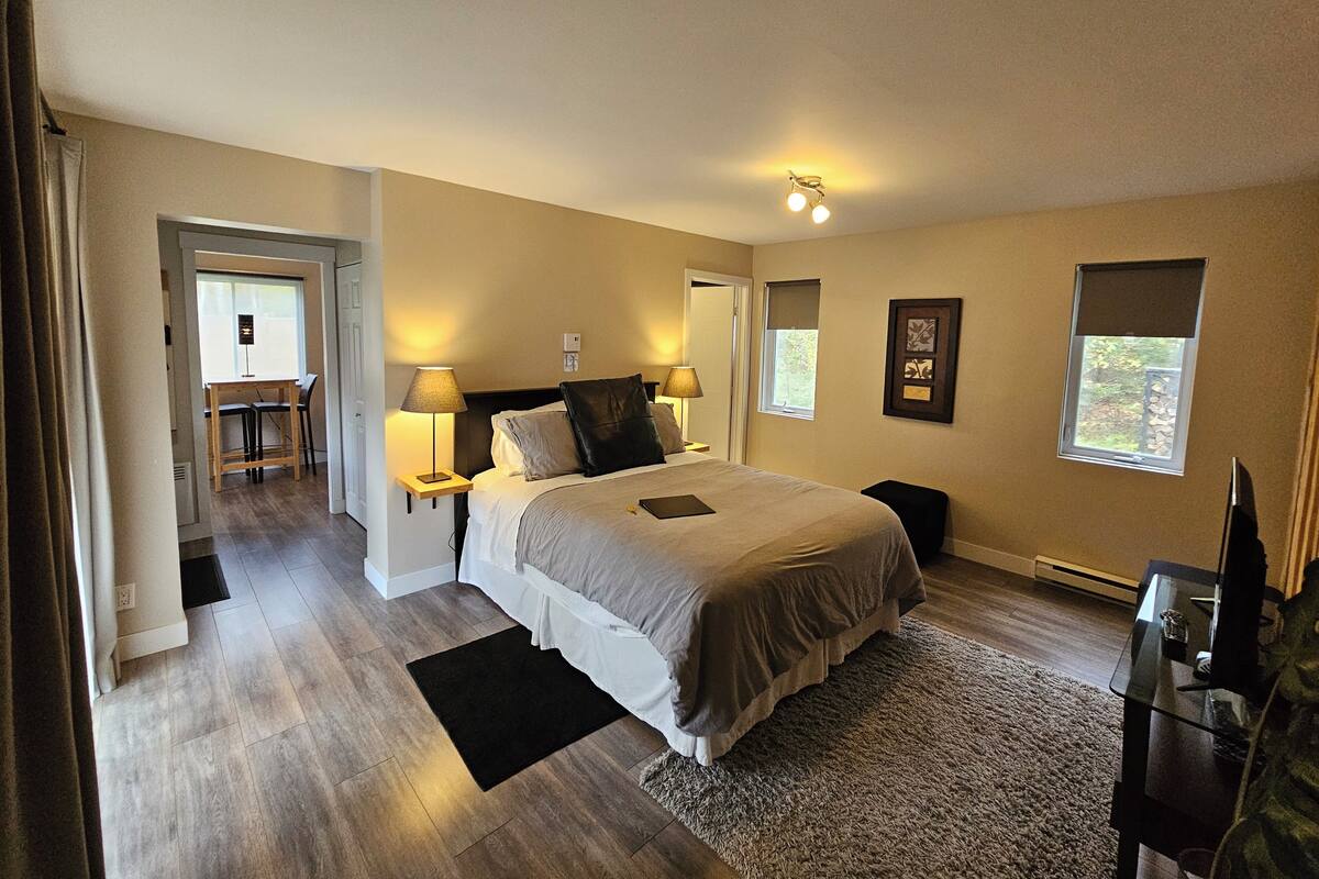 Une chambre à coucher avec un grand lit, des lampes de chevet, une petite table, une chaise et une fenêtre.