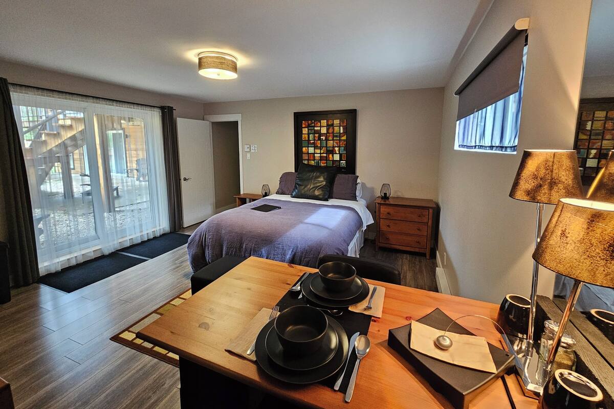 Une chambre d’hôtel avec un lit, une petite table avec un service à thé, une table de chevet et une fenêtre avec des rideaux.