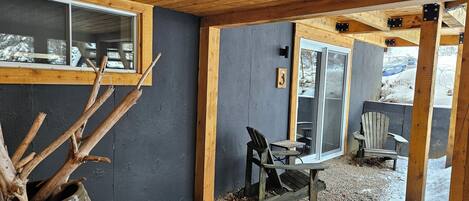 Una cabaña de madera con un ventanal grande, una silla de madera y un cartel con el número 3 en la pared.