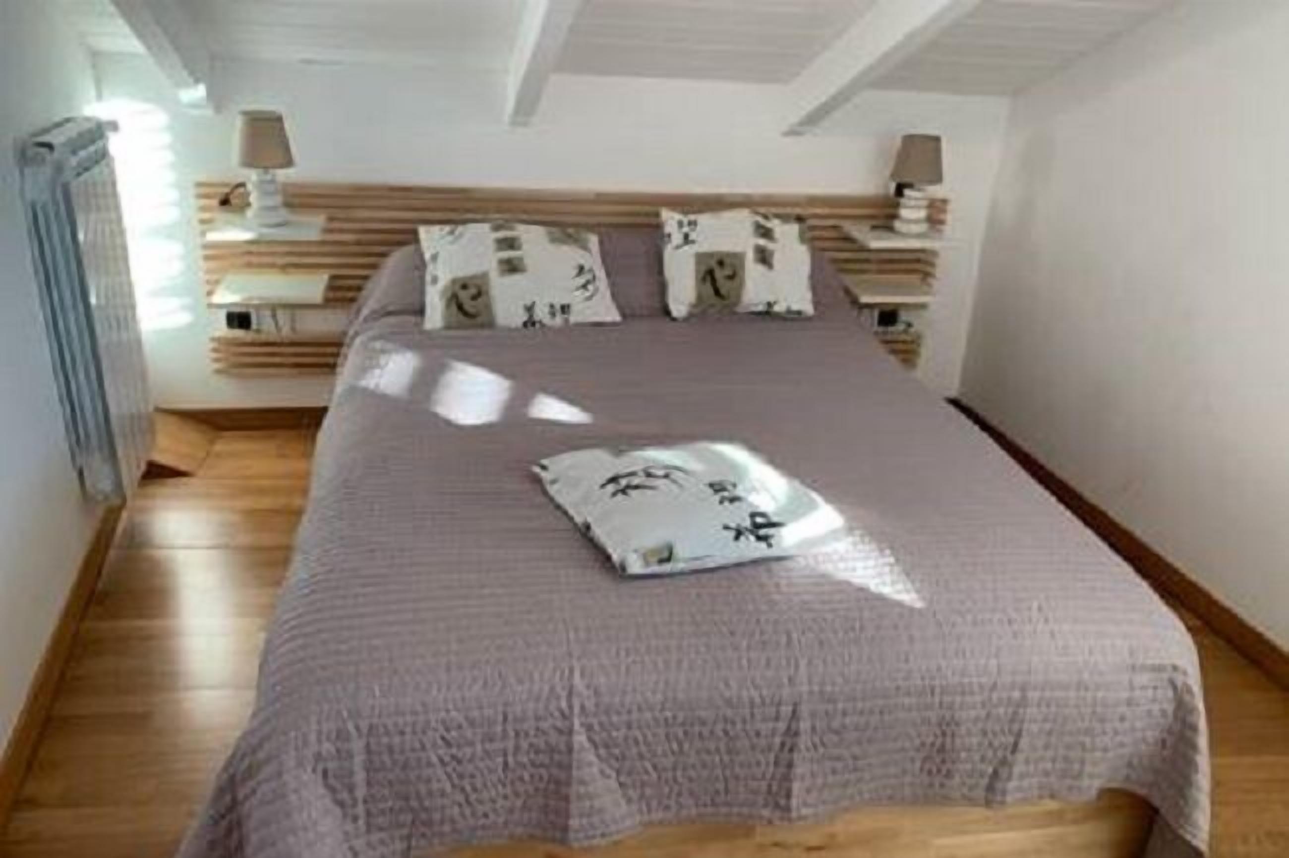 Un dormitorio con cama, cabecero de madera, mesitas de noche y un radiador.