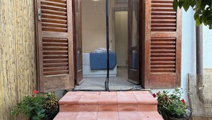 A set of terracotta steps leading to a wooden door with a glass panel, flanked by bamboo fencing and potted plants. - Villa Asia (Massa Lubrense)