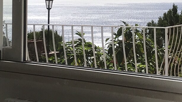 A balcony with a view of the sea, a street lamp, and greenery. - Villa Asia (Massa Lubrense)