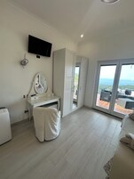 Un dormitorio moderno con un amplio ventanal corredero que da a un balcón con vistas al océano.