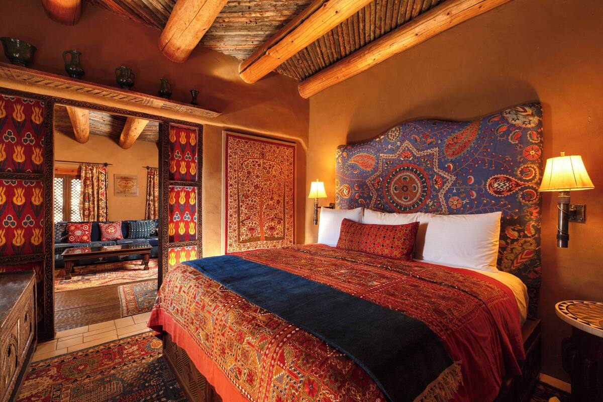A traditional room with a large bed, ornate headboard, and a patterned rug.