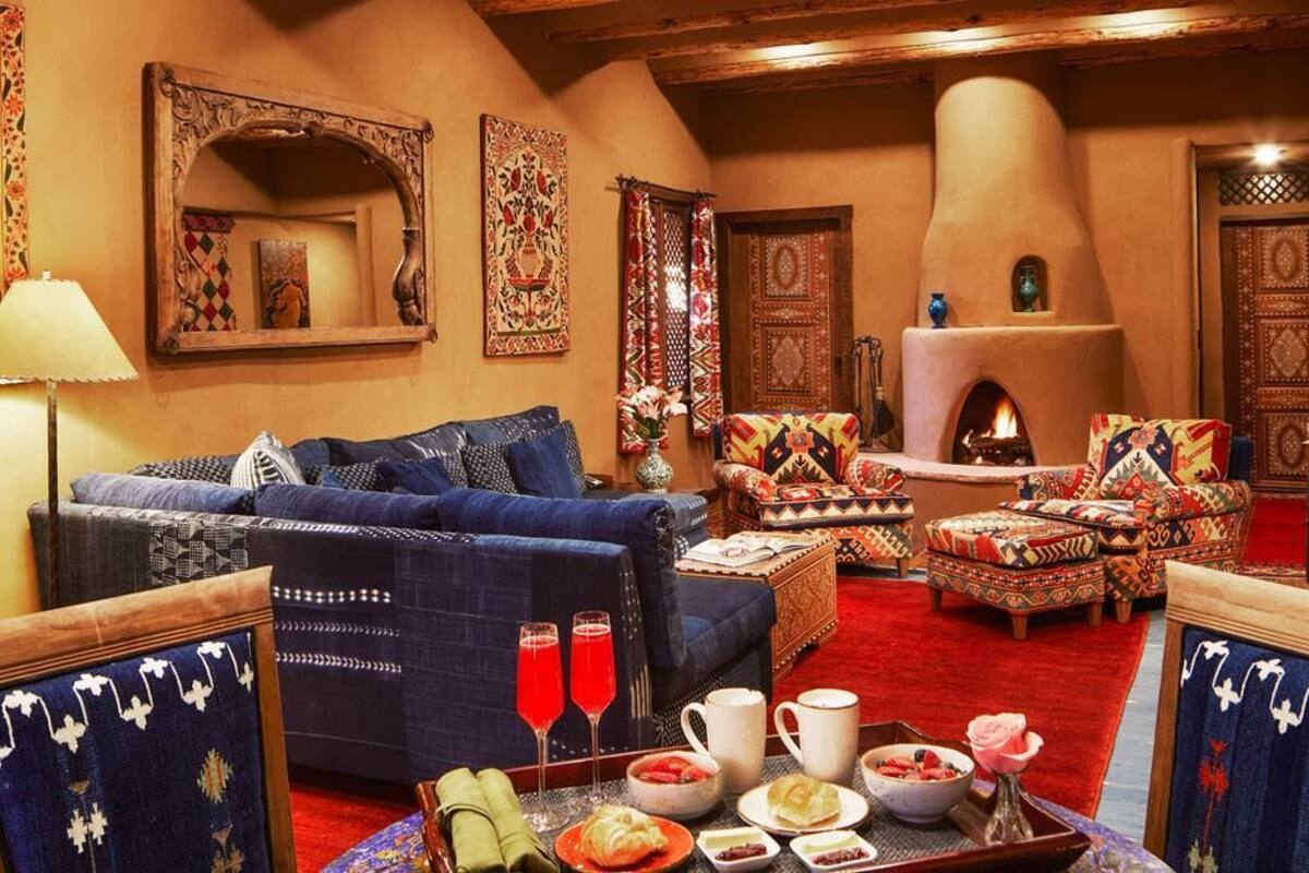A traditional living room with a sofa, armchairs, a fireplace, and a dining area with a tray of food and drinks.