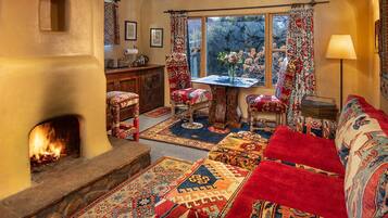 A cozy living room with a fireplace, patterned rugs, a sofa, and a dining table.