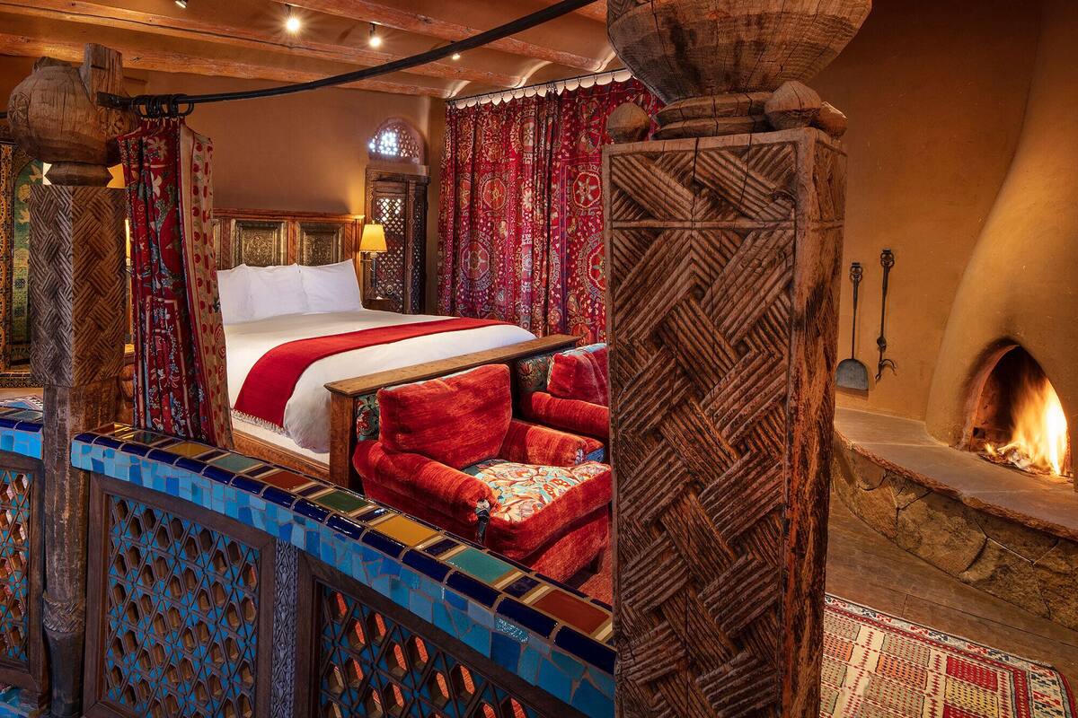A traditional room with a bed, a fireplace, and a decorative wall.