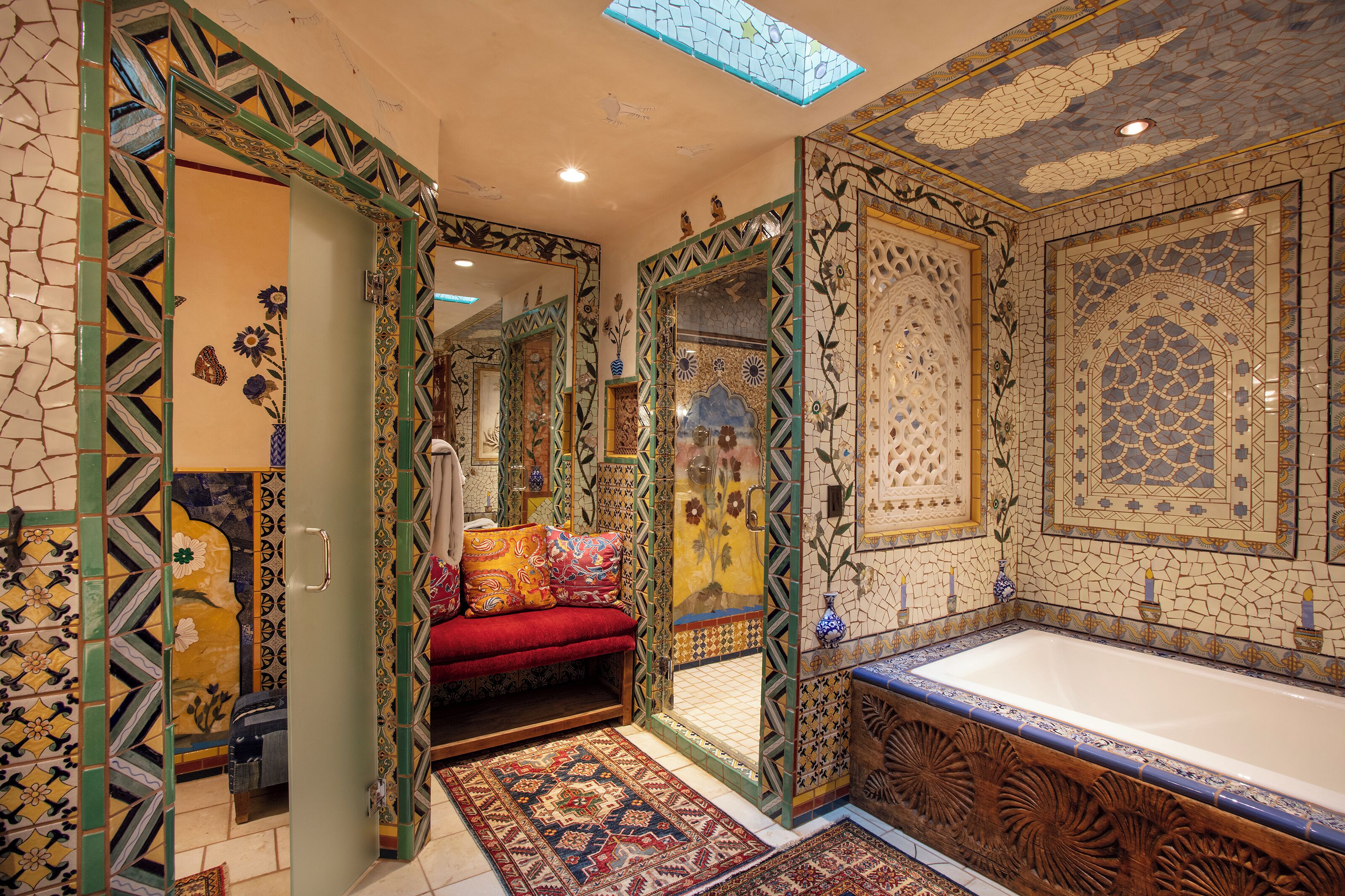 Une salle de bain luxueuse avec une grande baignoire, des carreaux décoratifs et un banc rouge.