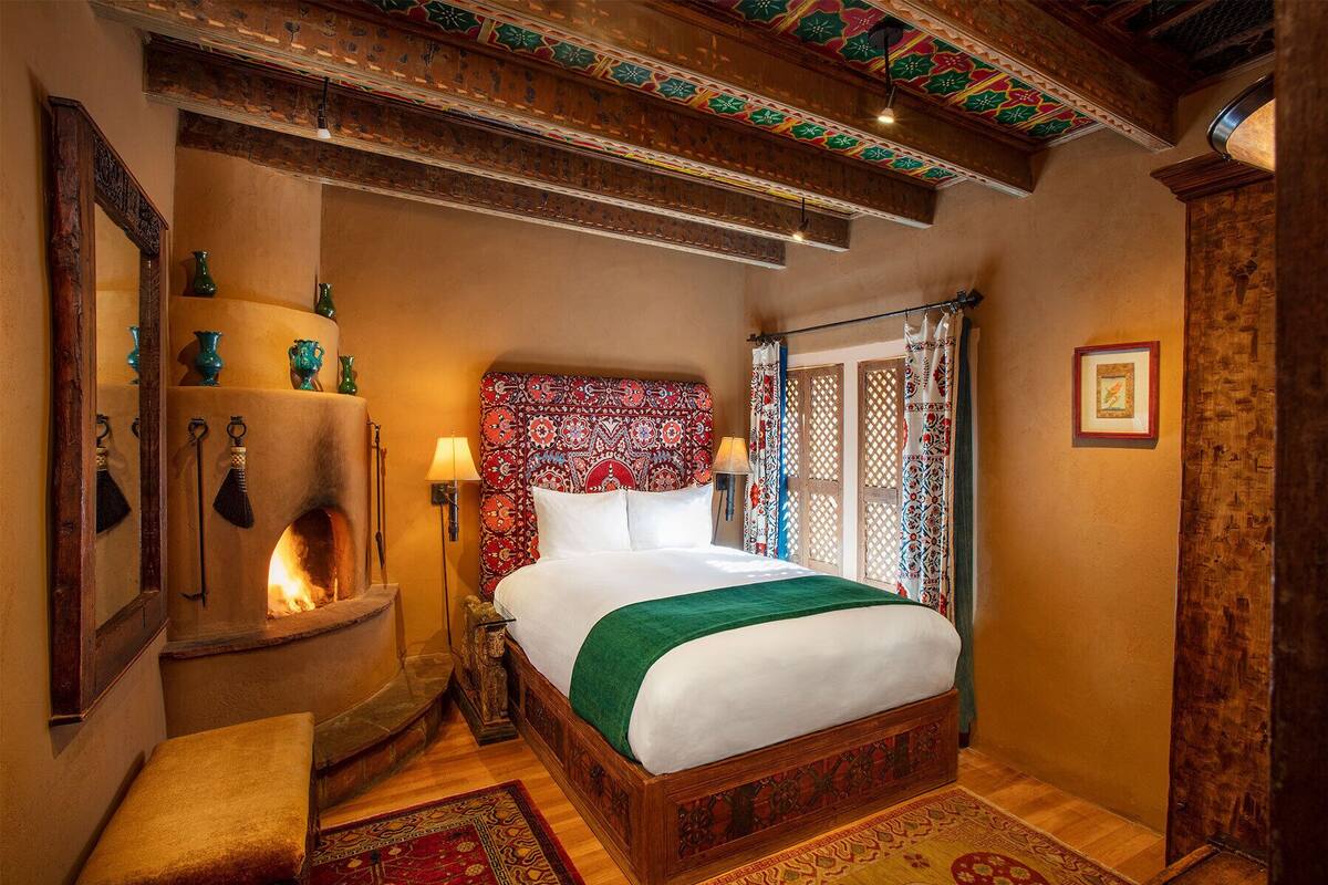 A traditional room with a bed, a fireplace, and a patterned ceiling.