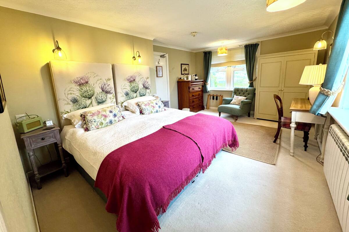 Une chambre à coucher comprenant un lit, une table de chevet, une commode, une chaise et un bureau avec une lampe.