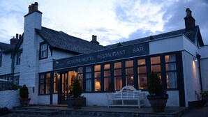 Et hotel med bar, store vinduer og en bænk udenfor.