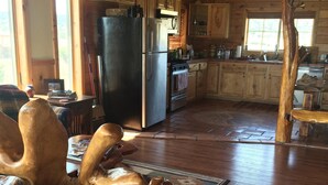 A spacious kitchen with wooden cabinets, a stainless steel refrigerator, and a large wooden dining table. - Off the Grid, secluded, Hamm's Hideaway (quemado)