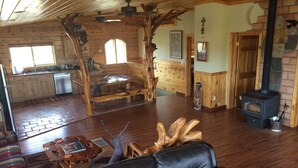 A cozy cabin interior with a fireplace, wooden furniture, and a dining area. - Off the Grid, secluded, Hamm's Hideaway (quemado)