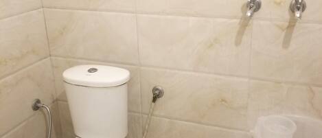 Een badkamer met toilet, douche en een zeepdispenser.