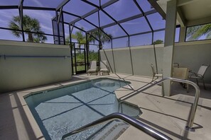A pool area with clear glass walls, lounge chairs, and a metal railing.