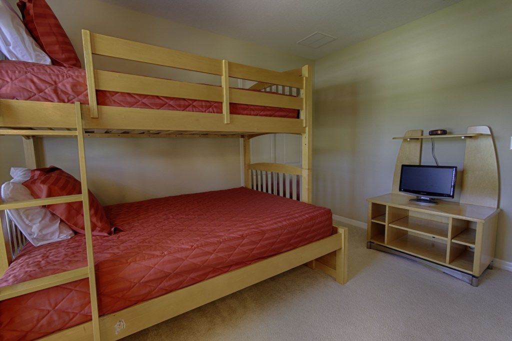 A bunk bed room with a desk and a computer monitor.