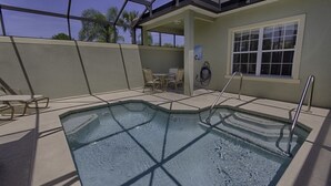 A pool area with a glass enclosure, a table and chairs, and a window with blinds.
