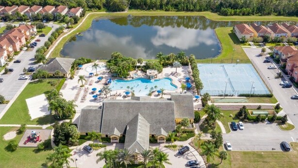An aerial view of a resort with a central swimming pool, multiple guest villas, and a parking area.