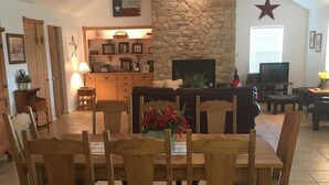 A dining area with a stone fireplace, wooden dining table, and chairs.