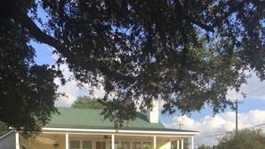 A two-story house with a green roof and a covered porch.