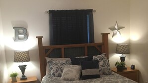 A bedroom with a bed, two bedside tables, a ceiling fan, a star decoration, and a letter 'B' on the wall.