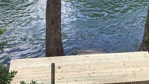 A wooden deck overlooking a body of water with trees in the background.