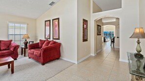 A spacious living room with a red sofa set, a coffee table, and framed artwork on the walls. - 4BR Pool Home Rolling Hills by SHV-7979 (Kissimmee)