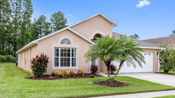 A single-story house with a beige exterior, a front garage, and a well-maintained lawn with various plants. - 4BR Pool Home Rolling Hills by SHV-7979 (Kissimmee)