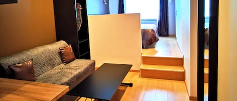 A modern living room with a sofa, a coffee table, and a staircase leading to a bedroom.