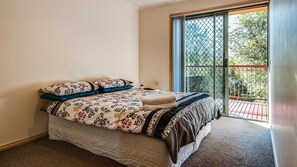 A bedroom with a bed, a window, and a view of a balcony. - Findlay on the Bay - sleeps 8 (Cowes)