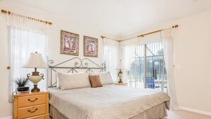 Ein Schlafzimmer mit einem großen Bett, zwei Nachttischen mit Lampen, einer Kommode mit Schubladen und zwei gerahmten Bildern an der Wand.