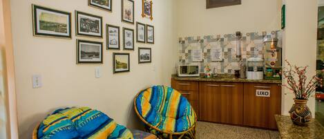 A kitchen with wooden cabinets, a microwave, and a coffee maker. There are two wicker chairs with colorful cushions.