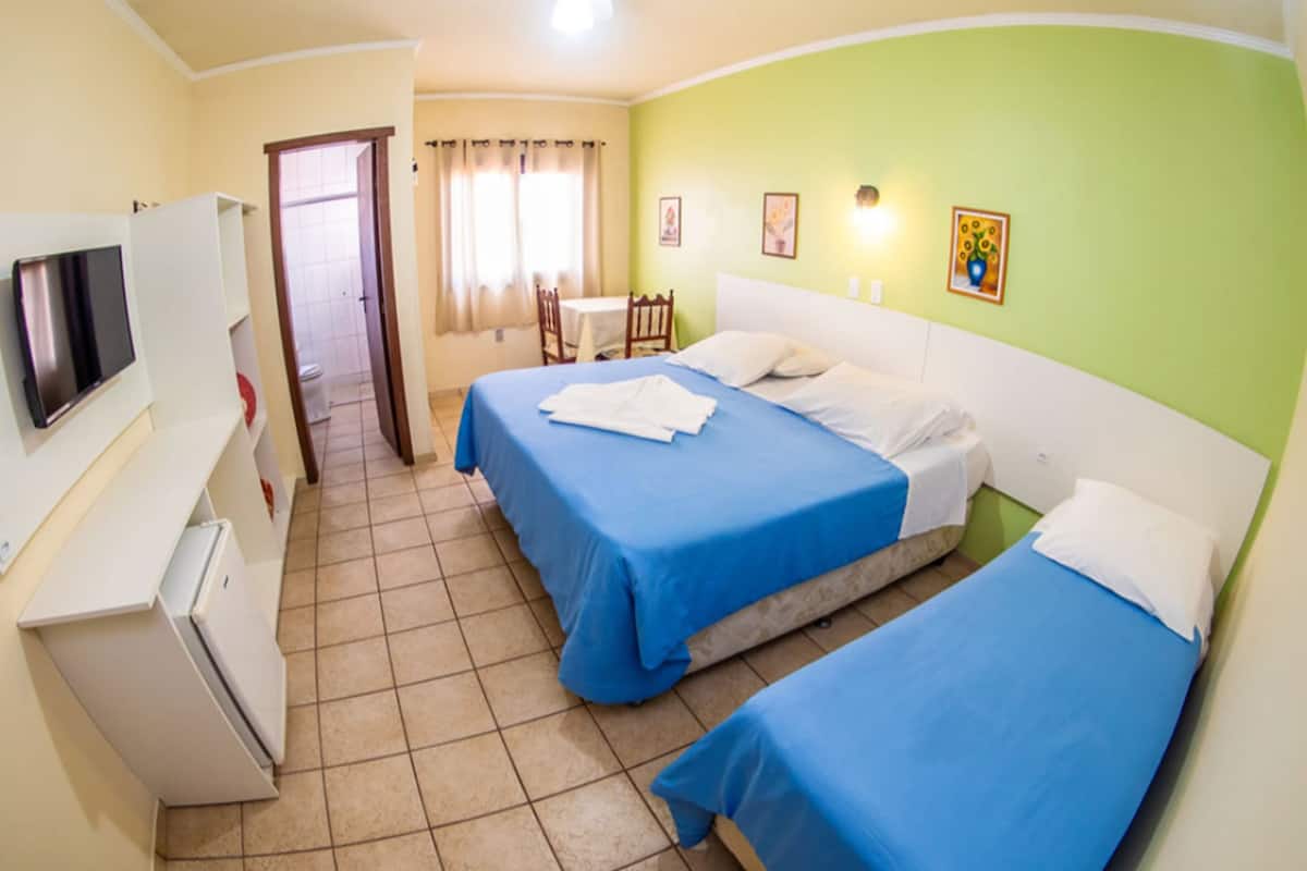A hotel room with two beds, a TV, a desk, and a bathroom visible through an open door.
