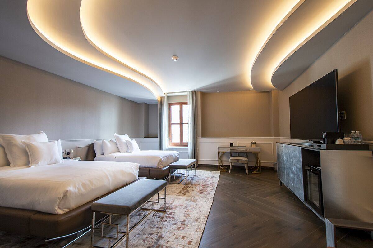 A modern hotel room with two beds, a desk, and a large TV.