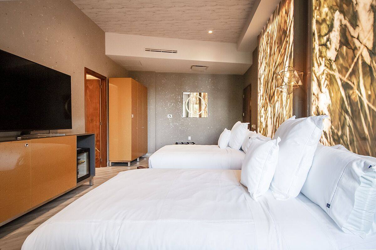 A hotel room with two beds, a TV, and a wooden cabinet.